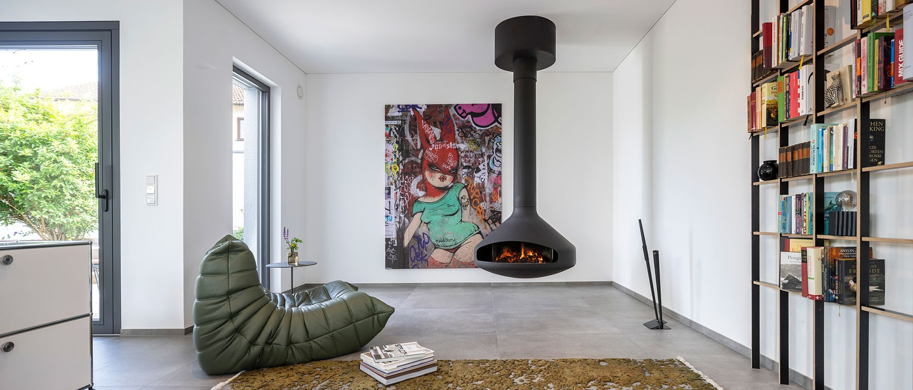 Gemütlicher Wohnbereich im nachhaltigen Atriumhaus mit modernem Kaminofen und Ausblick ins Atrium 