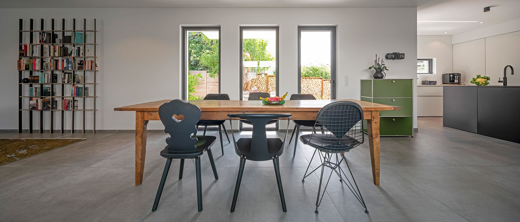 Essbereich im Atriumhaus mit Holztisch und drei schmalen Festverglasungs-Türen zum Garten 