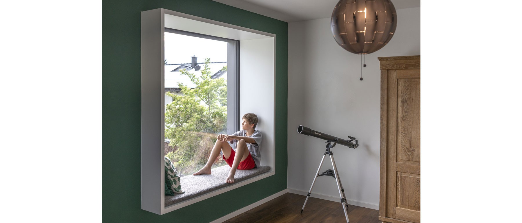 Kinderzimmer im Obergeschoss des Holzhauses mit Sitzfenster und viel Tageslicht 